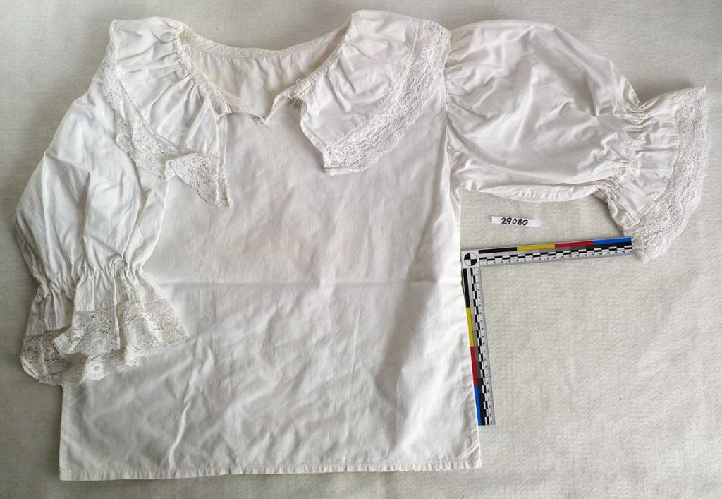 Plátěná halenka skutečského kroje s paličkovanou krajkou u krku a na rukávech, 1. pol. 20. stol.