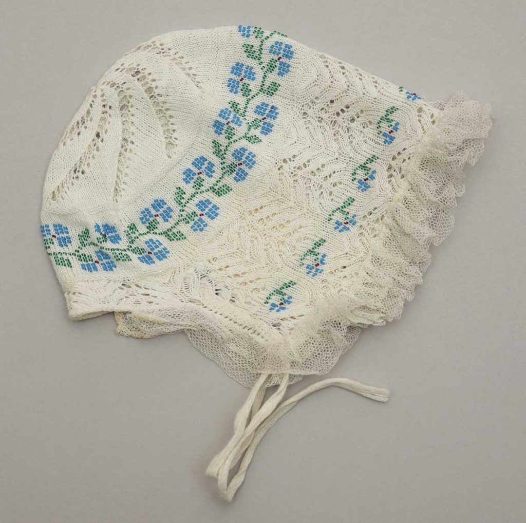 Dětský křestní čepeček zdobený drobnými korálky v pletené krajce, konec 19. století