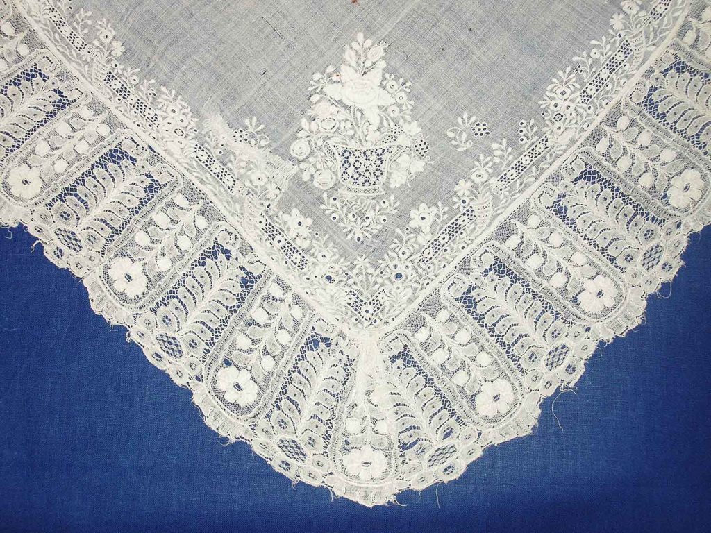 Šátek do pasu se strojovou krajkou na obvodu a bohatou bílou výšivkou s vyšívanými výplněmi tzv. katry. Rožnov